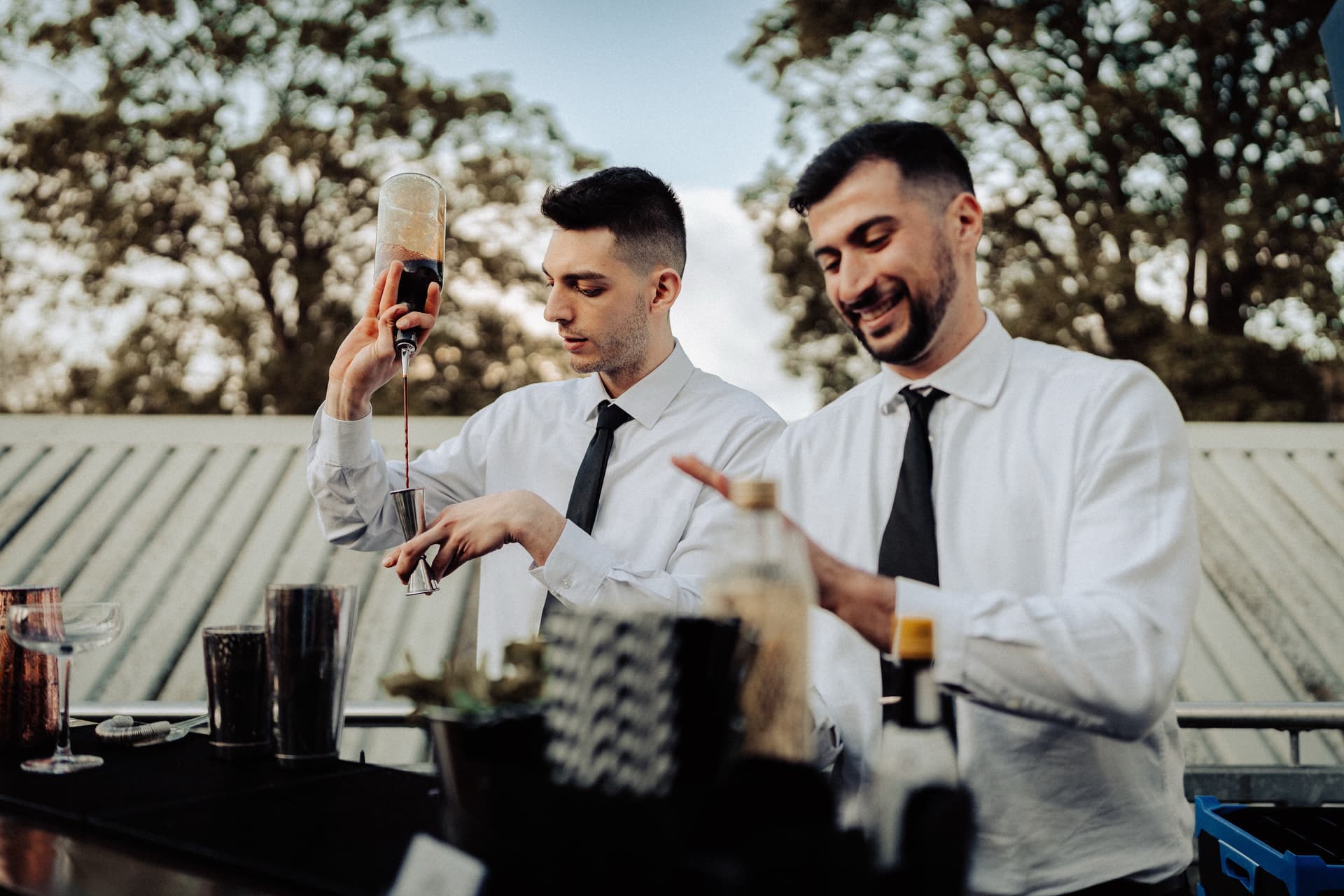 Two bartenders preparing drinks at customer's wedding cocktail bar